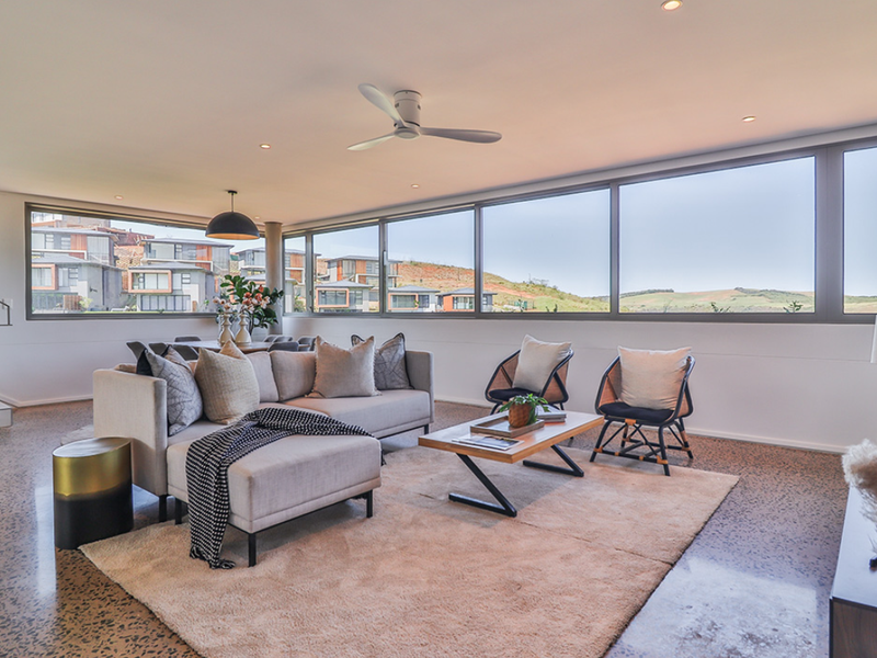 Spacious living area featuring polished concrete floors, extensive floor-to-ceiling windows with scenic views, and modern recessed lighting.