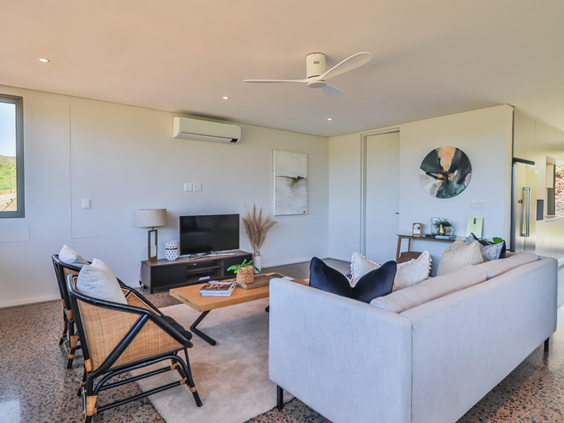 Modern open-plan living area featuring polished concrete floors, recessed lighting, a ceiling fan, and split-system air conditioning with a seamless flow to the kitchen.