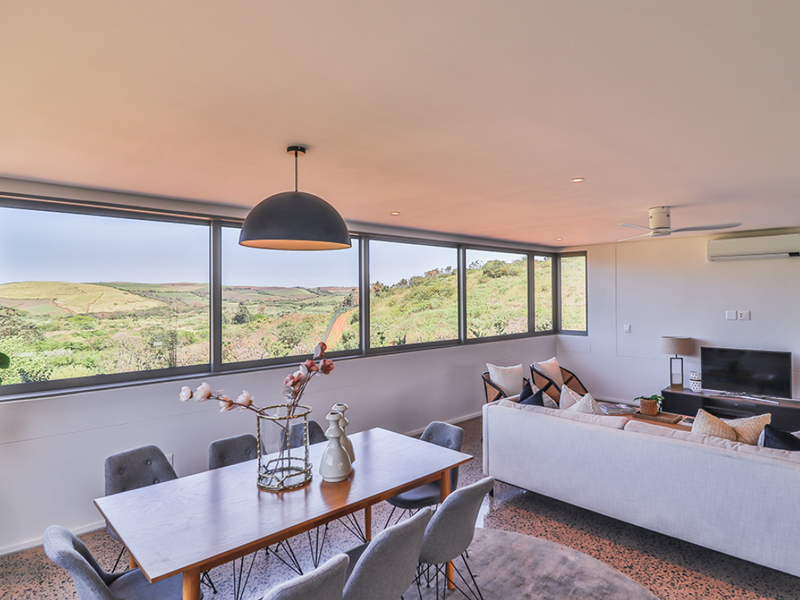 Spacious open-plan living and dining area featuring expansive panoramic windows with scenic views, terrazzo flooring, and modern climate control fixtures.
