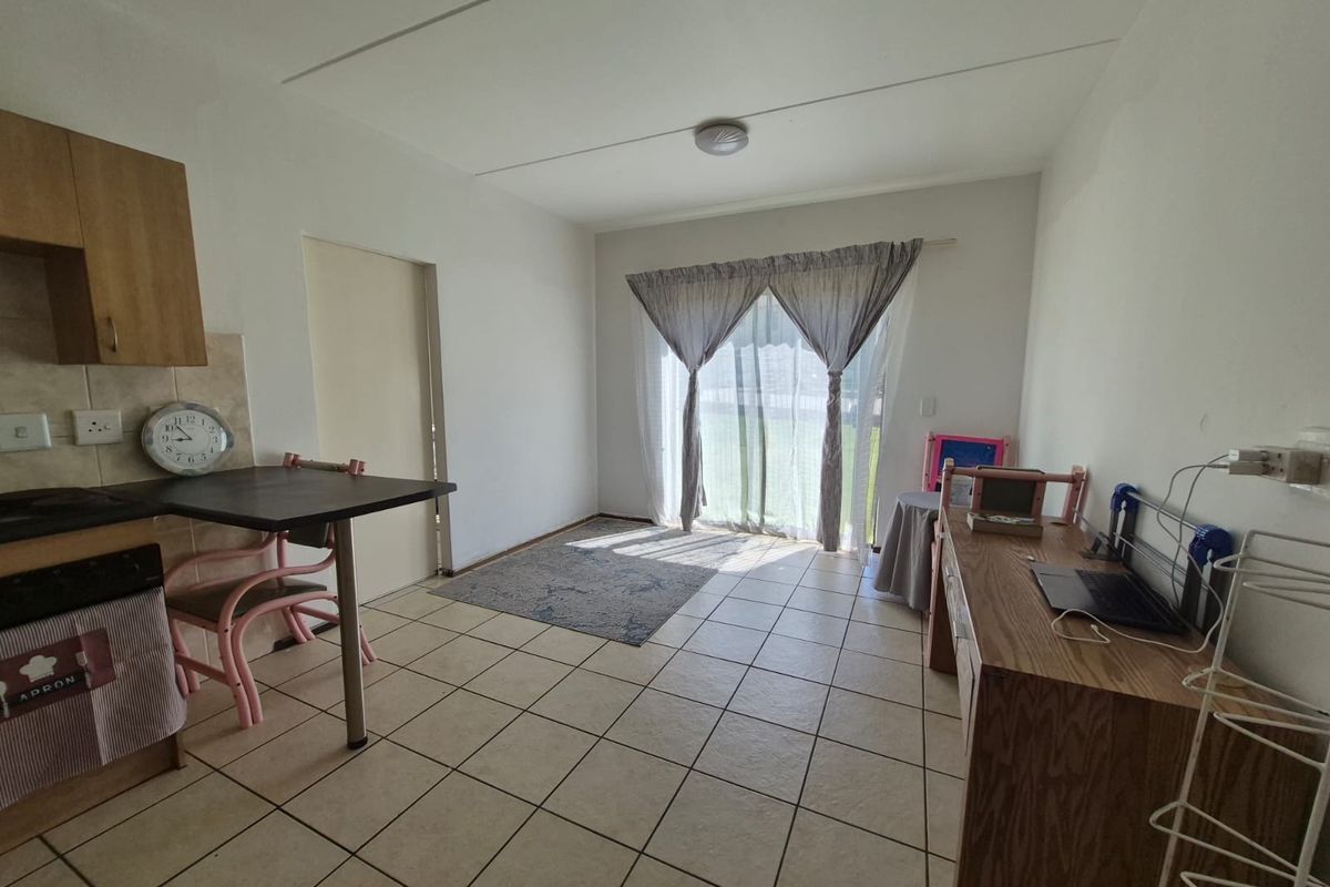 Open plan living and kitchen area featuring tiled flooring, built-in cabinetry, and a sliding glass door providing access to the exterior.