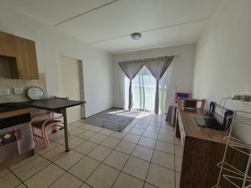 Open plan living and kitchen area featuring tiled flooring, built-in cabinetry, and a sliding glass door providing access to the exterior.