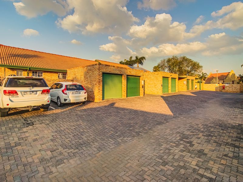Exterior view of a townhouse complex featuring face brick construction, multiple garage units, and a paved driveway area.