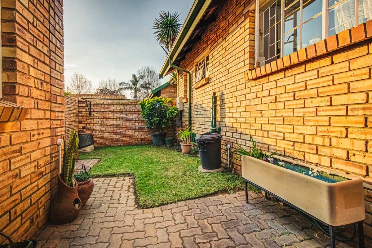 A private rear courtyard featuring a brick-walled perimeter, paved patio area, and a small lawn section, providing a functional outdoor space.