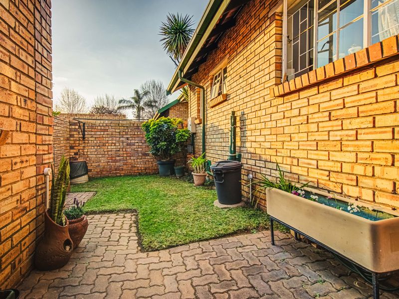 A private rear courtyard featuring a brick-walled perimeter, paved patio area, and a small lawn section, providing a functional outdoor space.