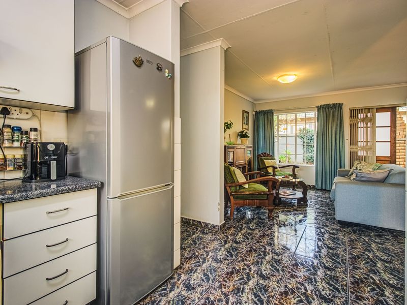 Open-plan kitchen and living area featuring tiled flooring, built-in cabinetry, and direct access to the outdoor space through a sliding door.