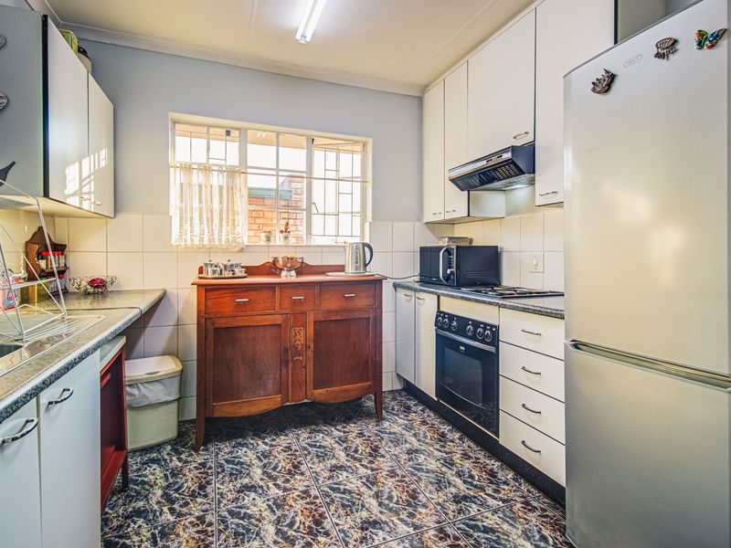 A functional kitchen featuring built-in cabinetry, a built-in oven with hob, extractor fan, and tiled splashbacks, with a window providing natural light.