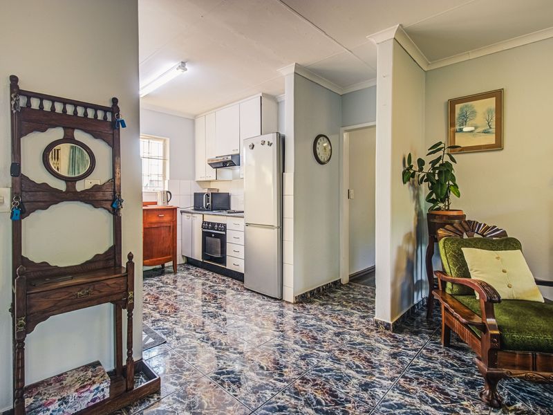 Open plan kitchen area featuring built-in cabinetry, oven, and extractor fan, finished with tiled flooring and coved cornicing.
