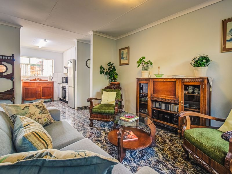 Open-plan living area featuring tiled flooring and a connected kitchen space with built-in cabinetry and appliances.