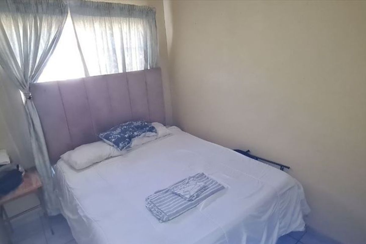 A compact bedroom featuring tiled flooring and neutral wall finishes, providing a functional sleeping space that could benefit from cosmetic updates.