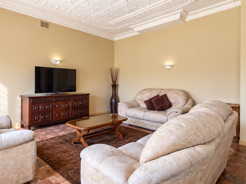 A living room featuring an ornate plaster ceiling, wall sconces, and tiled flooring, providing a classic foundation for interior updates.