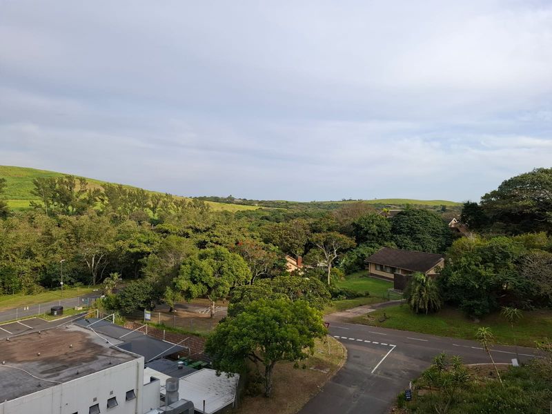 Elevated view overlooking the surrounding neighbourhood, lush green trees, and rolling hills.