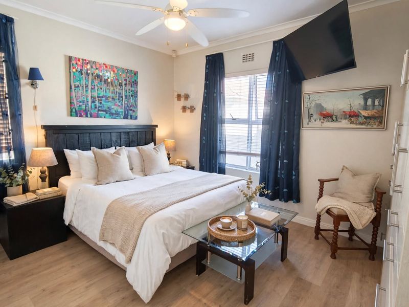 A well-maintained bedroom featuring laminate flooring, a ceiling fan, and built-in wardrobe storage, offering a comfortable and functional living space.