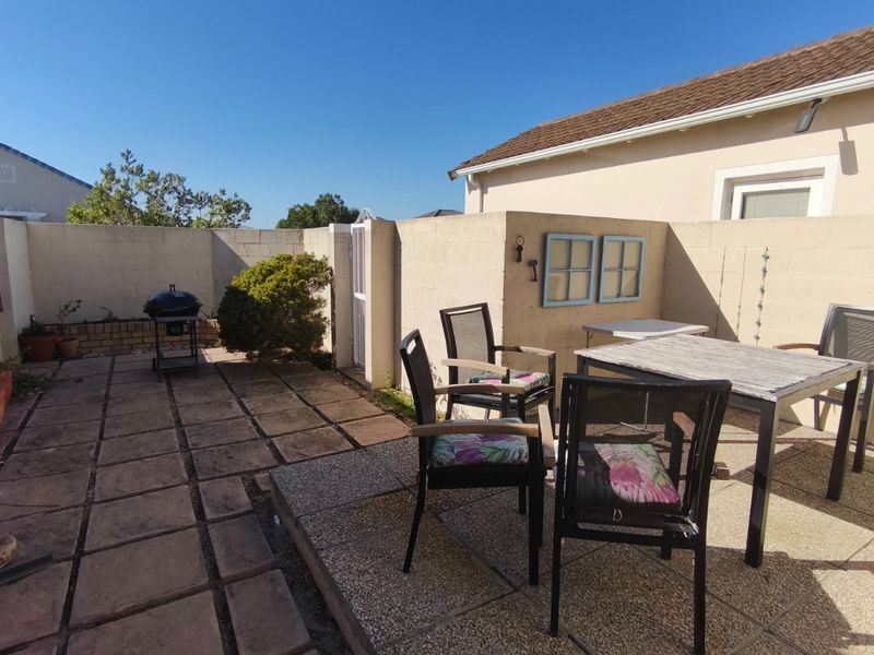 A paved outdoor patio area featuring a boundary wall and pedestrian access gate, suitable for outdoor dining and entertainment.