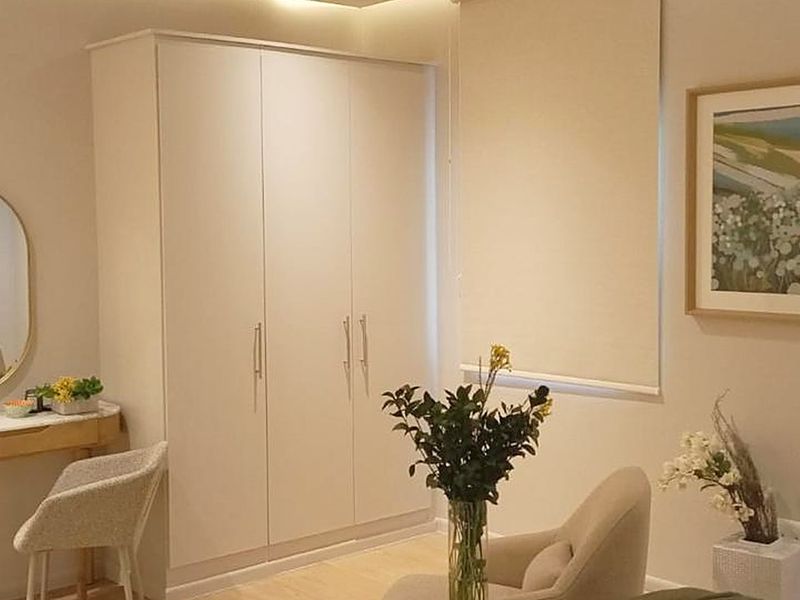 A well-maintained bedroom featuring a neutral color palette, built-in wardrobe storage, and recessed ceiling lighting.