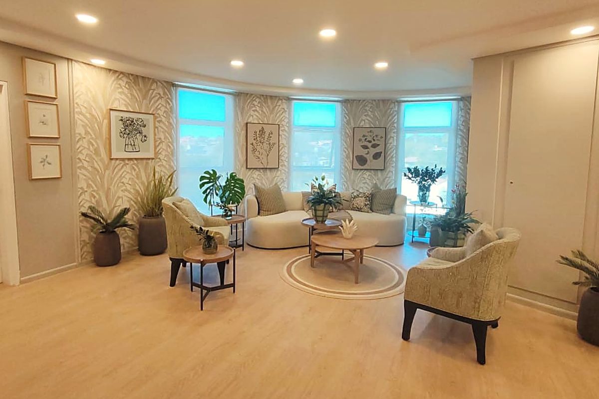A well-lit living room featuring modern laminate flooring, recessed downlights, and elegant patterned wallpaper, creating a bright and inviting atmosphere.