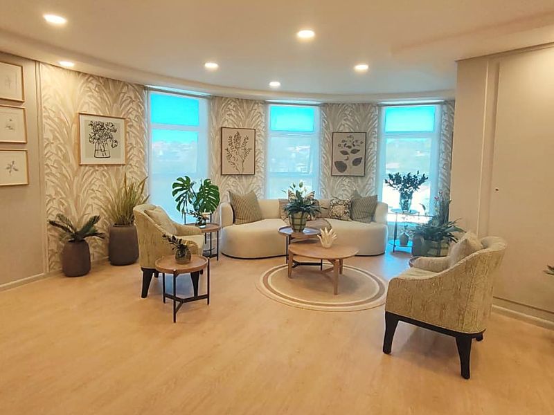 A well-lit living room featuring modern laminate flooring, recessed downlights, and elegant patterned wallpaper, creating a bright and inviting atmosphere.