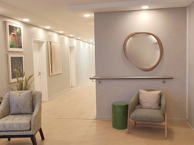 A well-lit, modern hallway featuring neutral wall finishes, recessed downlighting, and a safety grab rail, providing a clean and accessible transition space.