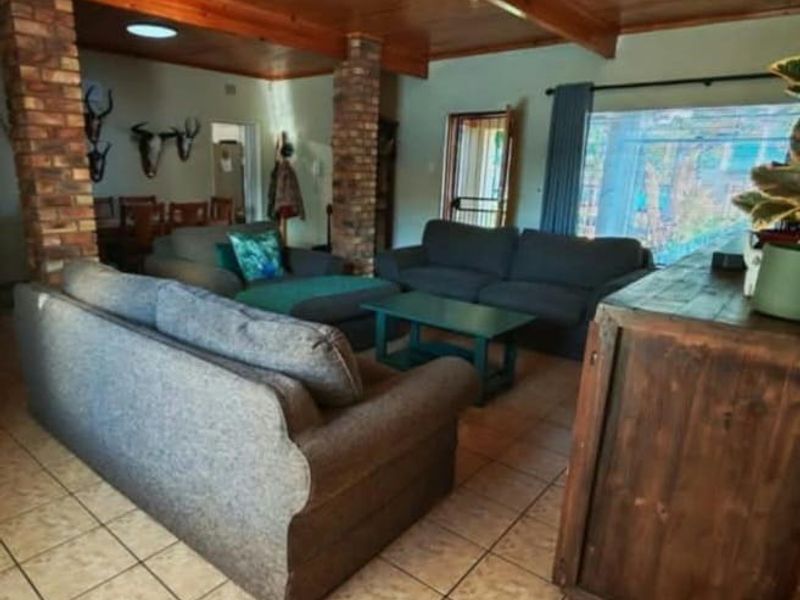 Open plan living area featuring a warm timber ceiling, exposed brick columns, and neutral ceramic floor tiles with access to the outdoor area.