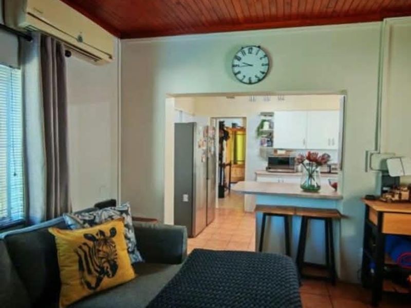 Open plan living area featuring a timber ceiling, tiled floors, and a breakfast bar connecting to the kitchen space.