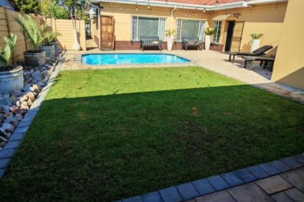 A well-maintained rear garden featuring a swimming pool, paved patio area, and manicured lawn, perfect for outdoor entertaining.