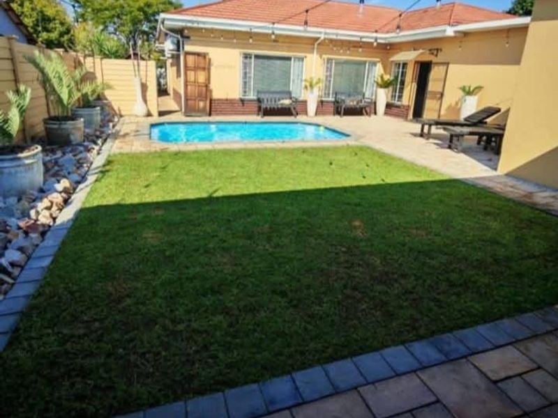 A well-maintained rear garden featuring a swimming pool, paved patio area, and manicured lawn, perfect for outdoor entertaining.