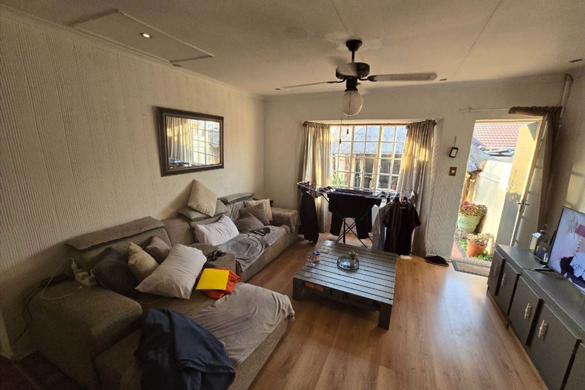A living room featuring laminate flooring, a ceiling fan, and textured wall finishes with direct access to an outdoor area.