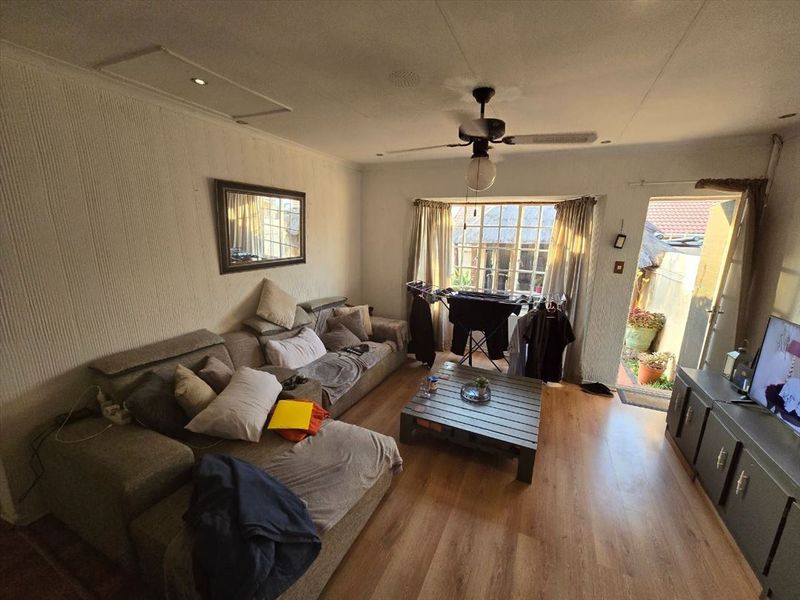 A living room featuring laminate flooring, a ceiling fan, and textured wall finishes with direct access to an outdoor area.