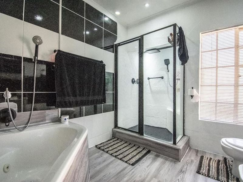 Modern bathroom featuring a bathtub, separate shower enclosure, toilet, and bidet with contrasting black and white wall tiling.