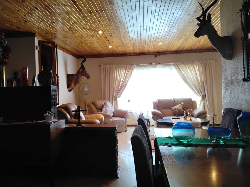 Open plan living and dining area featuring a timber tongue and groove ceiling, tiled flooring, and a brick partition wall.
