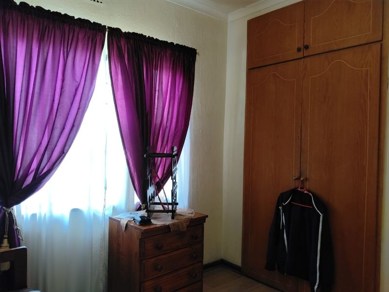A bedroom featuring built-in wooden cupboards and laminate flooring, offering a functional space with natural light.