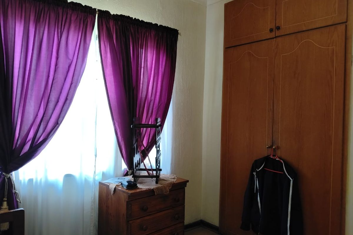 A bedroom featuring built-in wooden cupboards and laminate flooring, offering a functional space with natural light.