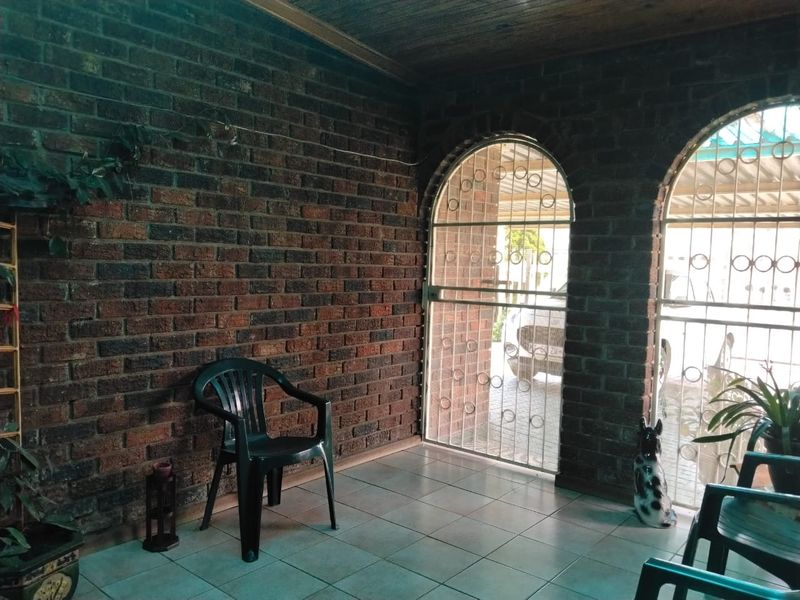 A covered patio area featuring exposed brick walls, arched security gates, and tiled flooring, providing a functional outdoor transition space.