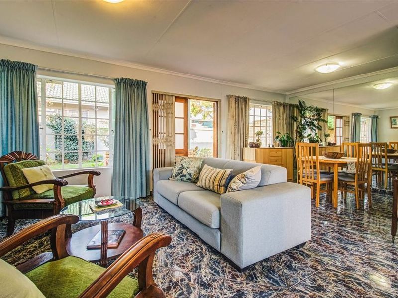 Open plan living and dining area featuring tiled flooring, a large mirrored wall, and direct access to the garden through sliding doors.