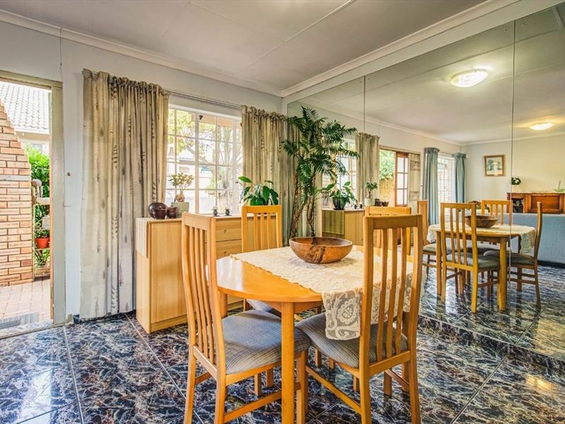 Dining area featuring a large mirrored wall, tiled flooring, and direct access to an outdoor patio space.