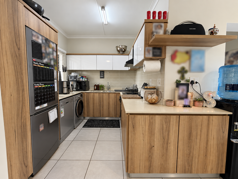 Modern kitchen featuring wood-grain cabinetry, white upper cabinets, tiled backsplash, integrated appliances, and durable ceramic floor tiles.