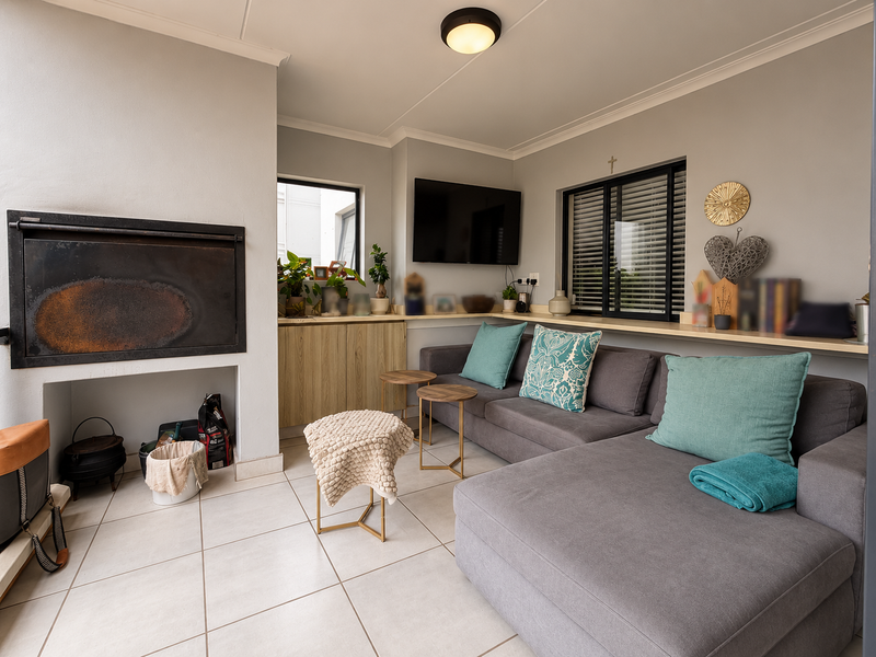 A covered patio area featuring a built-in braai, tiled flooring, and custom cabinetry, providing a functional space for outdoor relaxation and entertainment.