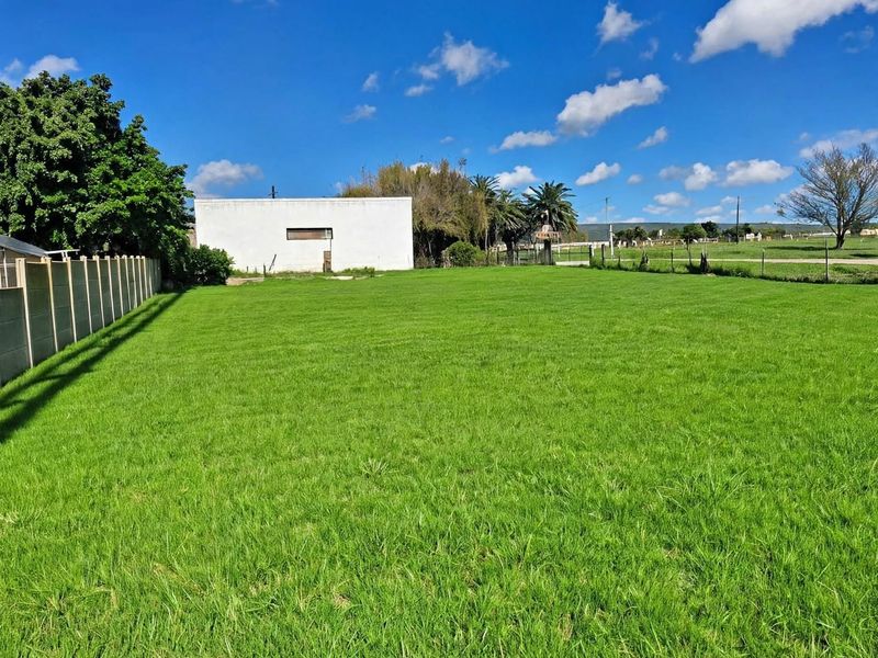 A spacious, well-maintained level grass plot featuring secure precast concrete boundary walls and wire fencing, ideal for residential development.