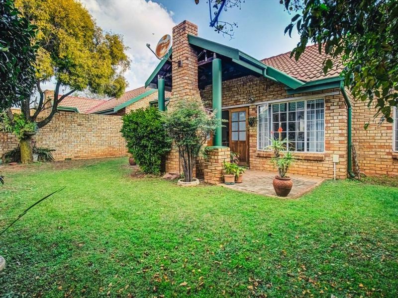 Rear view of the apartment featuring a brick facade, tiled roof, covered patio area, and a private garden with a boundary wall.