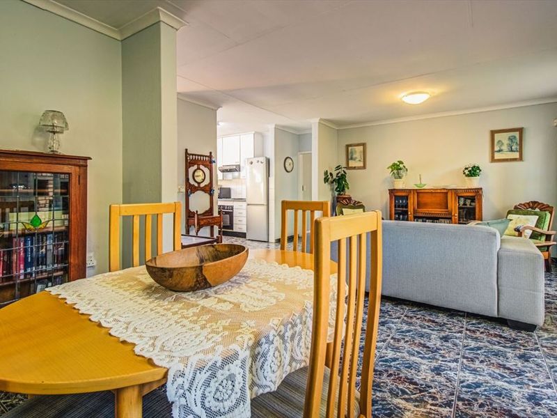 Open plan living and dining area featuring tiled flooring and coved ceilings, with a view through to the functional kitchen space.