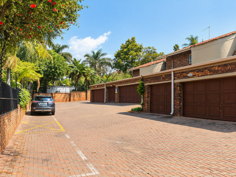 A view of the apartment complex driveway featuring a row of secure, brick-faced garages and paved access area.