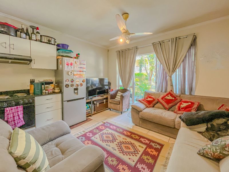 Open-plan living area featuring a compact kitchen with granite countertops and a sliding glass door leading to an outdoor space.