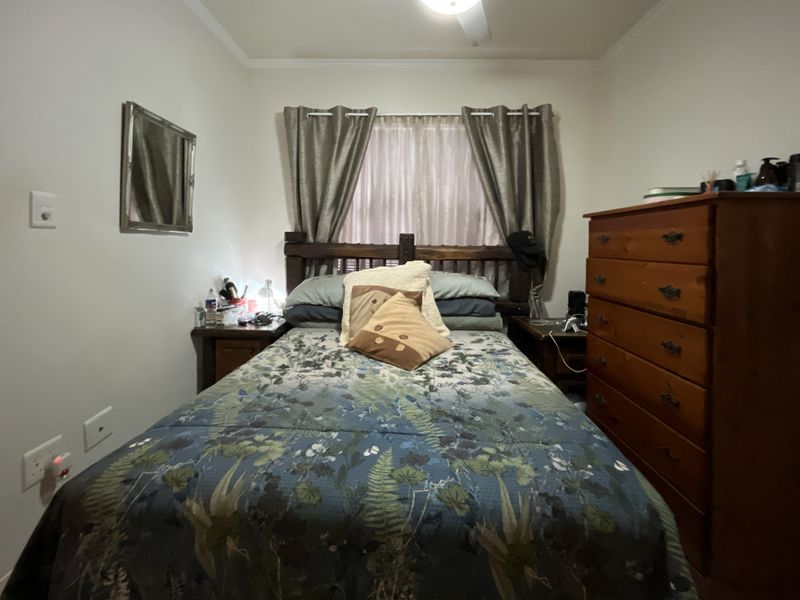 A standard bedroom featuring a ceiling fan and window treatments, providing a functional space for rest.