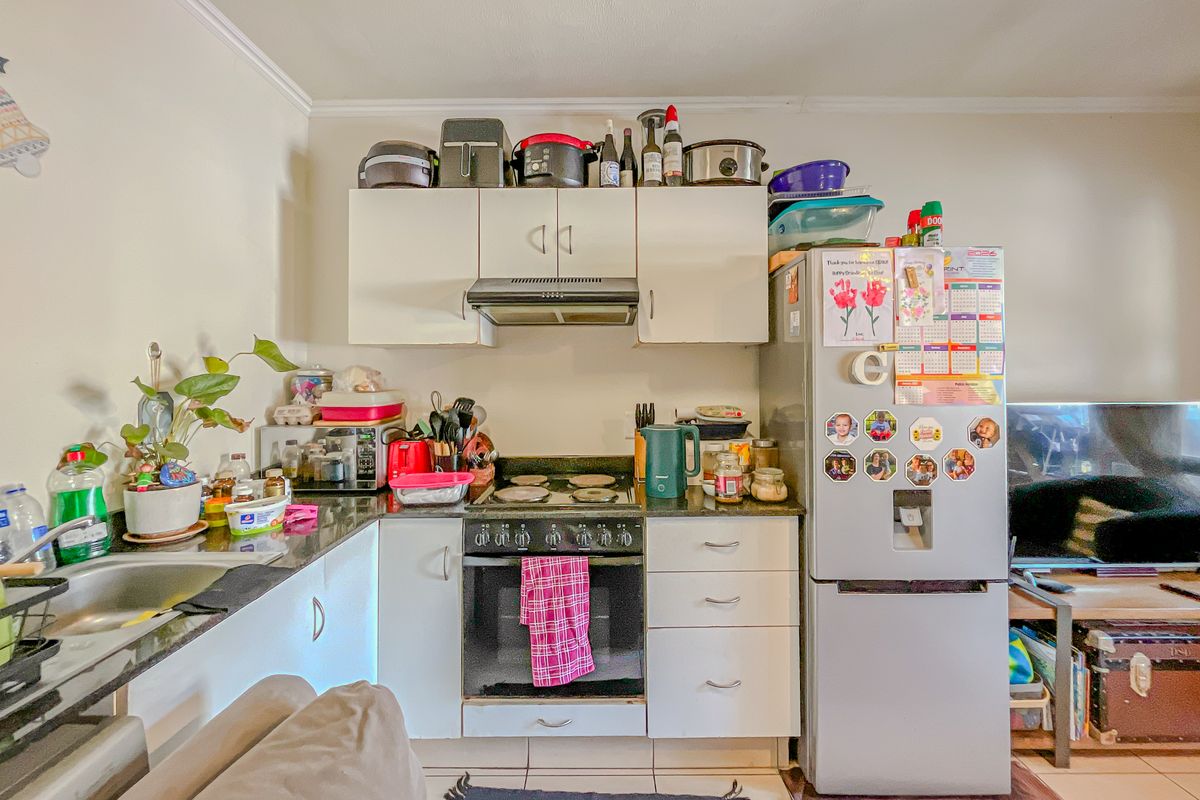 Compact kitchen featuring built-in cabinetry, granite countertops, an electric hob, and an integrated oven, providing a functional workspace within the open-plan living area.