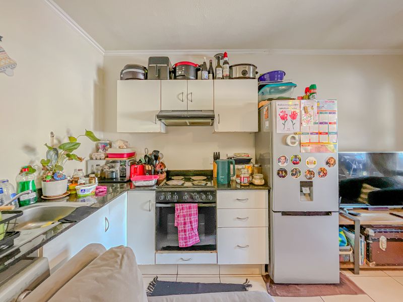 Compact kitchen featuring built-in cabinetry, granite countertops, an electric hob, and an integrated oven, providing a functional workspace within the open-plan living area.