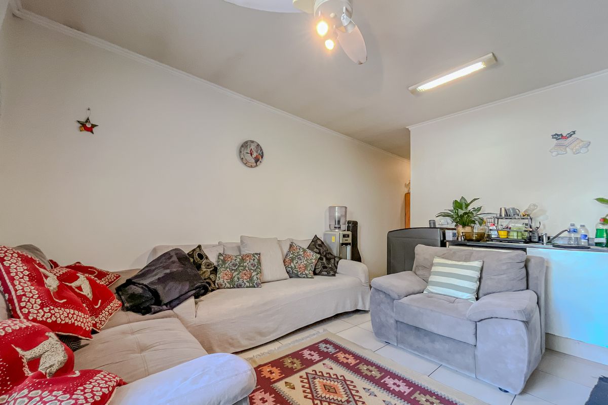 A living room area featuring tiled flooring, a ceiling fan, and a central light fixture, providing a functional and comfortable space.