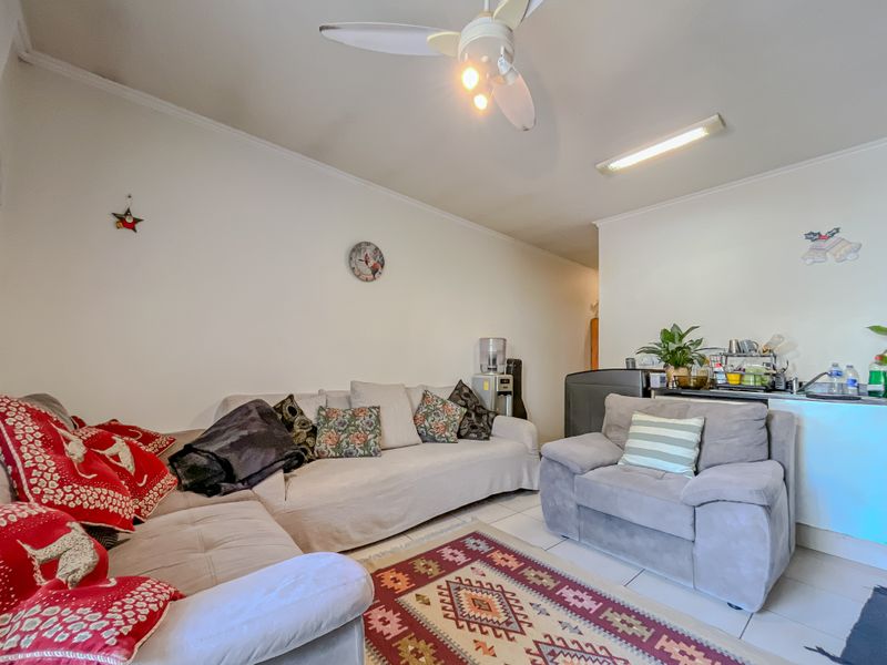 A living room area featuring tiled flooring, a ceiling fan, and a central light fixture, providing a functional and comfortable space.