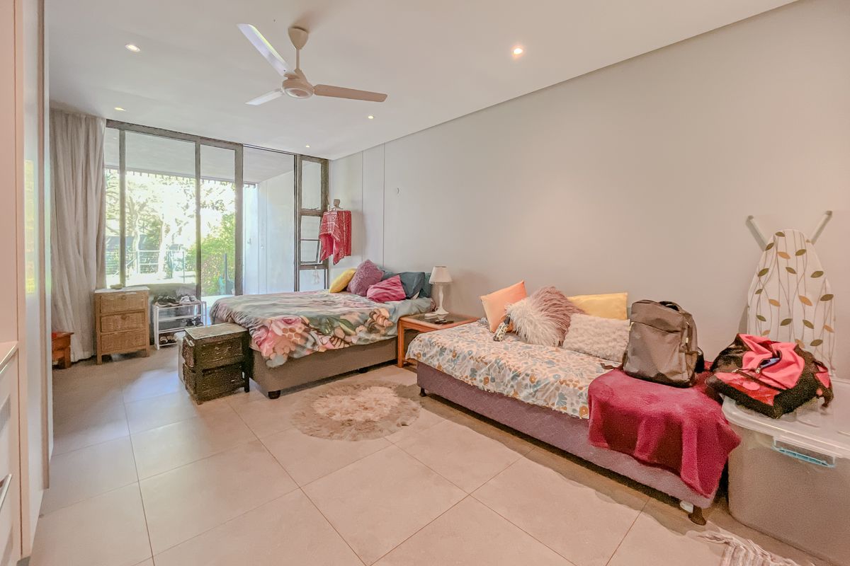 Spacious bedroom featuring large sliding glass doors leading to an outdoor area, neutral tiled flooring, and a ceiling fan.