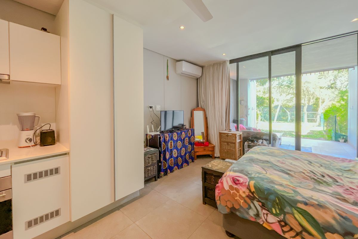 A bedroom featuring built-in cupboards, a ceiling fan, air conditioning, and large sliding glass doors providing access to an outdoor patio area.