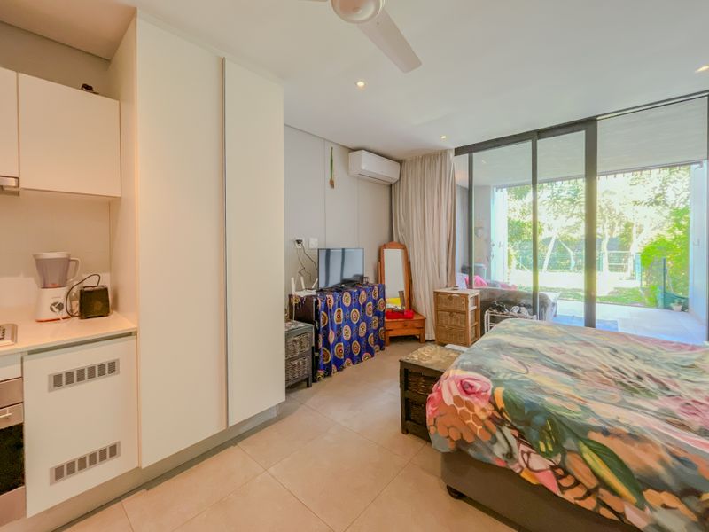 A bedroom featuring built-in cupboards, a ceiling fan, air conditioning, and large sliding glass doors providing access to an outdoor patio area.