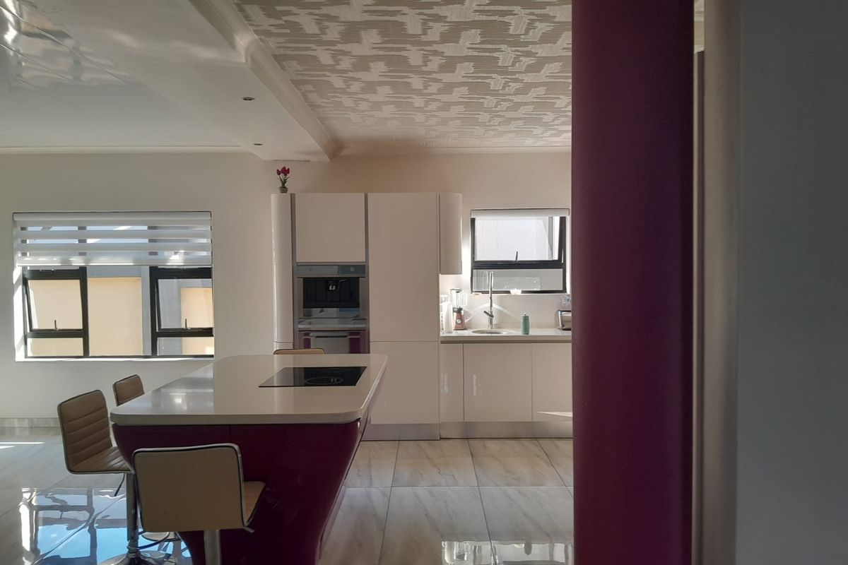 Modern kitchen featuring a central island with integrated cooktop, sleek cabinetry, built-in appliances, and polished tiled flooring.